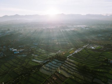 Aydınlık sisli ve parlak bulutlu Gede Dağı 'nın sabah manzarası dingin ve berrak güzelliği yakalıyor.