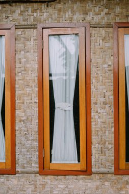 Bambu duvarlı bir pencere, kırsal bir evin huzurlu manzarasını yakalıyor.