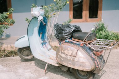 Antika Vespa scooter, aşınma ve gözyaşı belirtileri gösteriyor, bir şehir ortamında nostalji ve karakter çağrıştırıyor