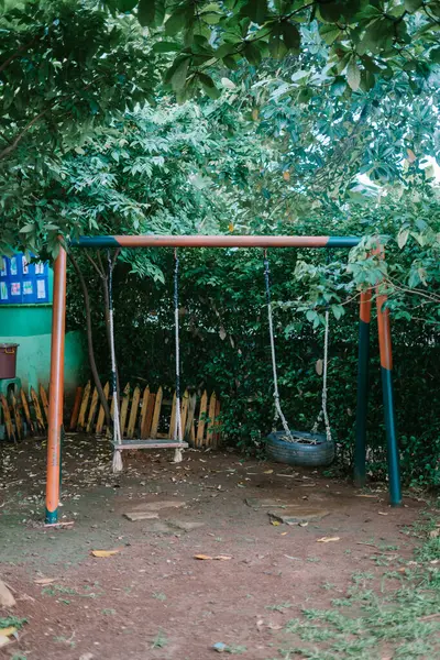 stock image Children's playground swing with a seat made from a recycled tire and wood, combining fun and sustainability