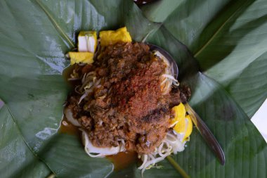 Muz yapraklarına sarılı kızarmış fasulye filizleri, canlı renkler ve dokularla geleneksel bir sunum sergiliyor, aşçılık için mükemmel.