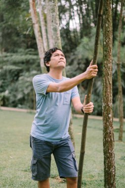 Elinde ağaç gövdesi olan Güneydoğu Asyalı bir adam doğayla bir anlık bir bağ yakalıyor. Çevre ve açık hava için mükemmel.