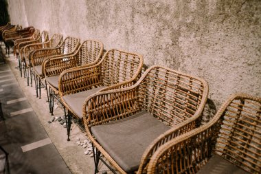 Düzgün bir şekilde dizilmiş rattan sandalyeler, doğal zarafetlerini sergiliyorlar ve şık bir ortamda konforu davet ediyorlar.