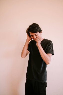 Güneydoğu Asyalı bir adam kafasını ve ağzını tutarak, bir anlık sıkıntı ya da derin düşünceyi yakalıyor, duygusal, portre ve yaşam tarzı projeleri için mükemmel..