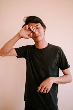 Kaşıntı yüzünden gözlerini ovuşturan Güneydoğu Asyalı bir adam, bir anlık rahatsızlık ya da rahatsızlık, sağlık, yaşam tarzı ve duygusal projeler için mükemmel.