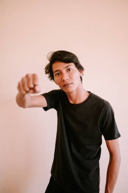 Güneydoğu Asyalı bir adam öne doğru yumruğunu sıkarak bir kararlılık ya da meydan okuma anı yakalıyor. Duygusal, portre ve motivasyon projeleri için mükemmel.