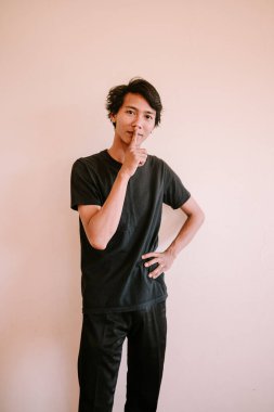 Güneydoğu Asyalı bir adam işaret parmağıyla dudaklarına dokunuyor. Sessizlik ve gizlilik için işaret veriyor. İletişim, yaşam tarzı ve portre projeleri için mükemmel..