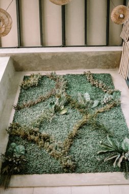 Duvar dekorasyonunda yapay bitkiler kullanılıyor, iç kısımlara yeşillik ve tarz katılıyor. Ev dekorasyonu, iç mekan estetiği ve yaratıcı tasarım unsurları için mükemmel bir tema.