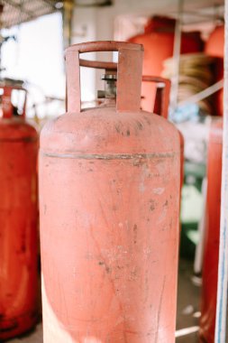 Dik duran büyük bir turuncu gaz silindiri, güvenlik ve yararlılığı vurguluyor. Endüstriyel ekipman, enerji ve ev gereçleri temaları için mükemmel.