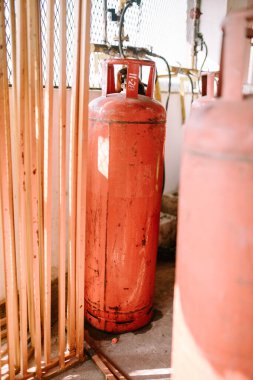 Dik duran büyük bir turuncu gaz silindiri, güvenlik ve yararlılığı vurguluyor. Endüstriyel ekipman, enerji ve ev gereçleri temaları için mükemmel.