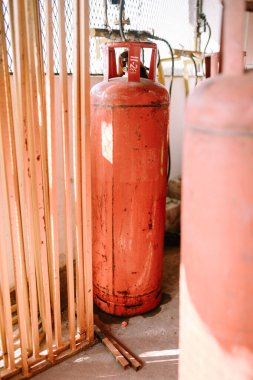 Dik duran büyük bir turuncu gaz silindiri, güvenlik ve yararlılığı vurguluyor. Endüstriyel ekipman, enerji ve ev gereçleri temaları için mükemmel.