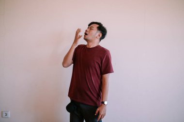 Güneydoğu Asyalı bir adam yorgun bir ifadeyle ve sarkık gözleriyle uykulu görünüyor. Yorgunluk, rahatlama ve dinlenme temaları için mükemmel..