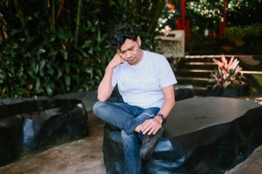 Güneydoğu Asyalı bir adam, düşünceli ve rahat bir görünüm sergiliyor. Düşünce, rahatlama ve içgözlem temaları için mükemmel.