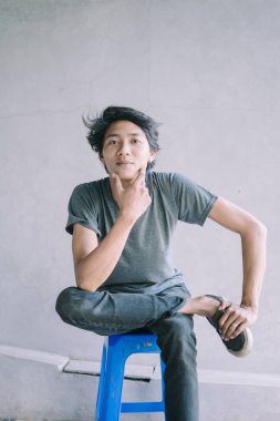 Mavi plastik bir sandalyede ciddi ciddi oturan Güneydoğu Asyalı bir adam bir anlık tefekkür ya da odaklanma görüntüsü yakalıyor. Yaşam tarzı, portre ve günlük yaşam projeleri için mükemmel.