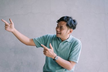 Tarafsız bir ifade sergileyen Güneydoğu Asyalı bir adam, iki parmağını kaldırarak sakin ya da sıradan bir jest anı yakalıyor. Yaşam tarzı, portre ve iletişim projeleri için mükemmel.