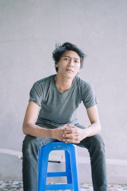 Mavi plastik bir sandalyede ciddi ciddi oturan Güneydoğu Asyalı bir adam bir anlık tefekkür ya da odaklanma görüntüsü yakalıyor. Yaşam tarzı, portre ve günlük yaşam projeleri için mükemmel.