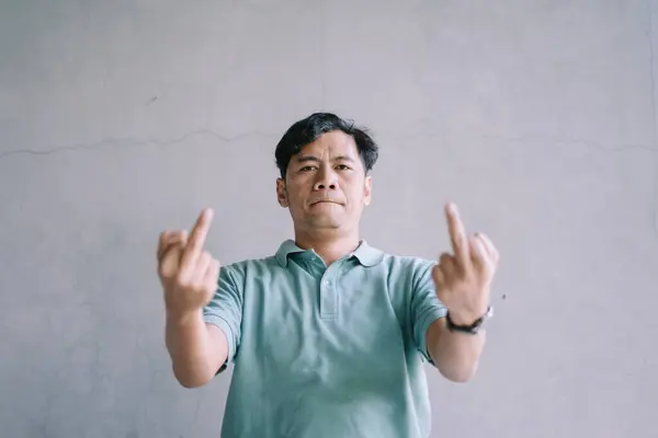 stock image A Southeast Asian man showing his middle finger, expressing defiance or frustration, perfect for emotional, rebellious, or edgy lifestyle projects