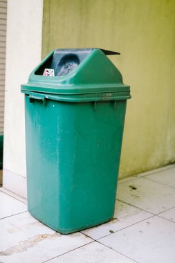 Yeşil plastik bir çöp kutusu, basit ve işlevsel, açık ya da kapalı alanda atık imhası için ideal. Temizlik, organizasyon ve çevre bilinci temaları için mükemmel