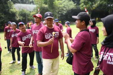 Bogor, 10 Ağustos 2024. Takım oluşturma faaliyetlerine katılan bir grup insan, takım çalışmasını ve iletişimi teşvik eden işbirlikçi oyunlara katılıyorlar. Şirket veya grup dinamiği temaları için ideal.