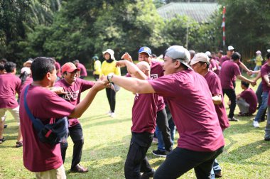 Bogor, 10 Ağustos 2024. Takım oluşturma faaliyetlerine katılan bir grup insan, takım çalışmasını ve iletişimi teşvik eden işbirlikçi oyunlara katılıyorlar. Şirket veya grup dinamiği temaları için ideal.