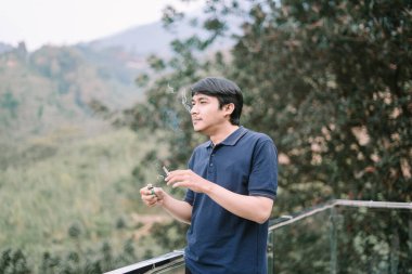 Sigara içen Güneydoğu Asyalı bir adam, rahat bir anda dumanın ince detaylarıyla yakalandı.