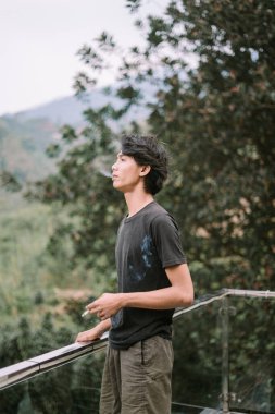 Sigara içen Güneydoğu Asyalı bir adam, rahat bir anda dumanın ince detaylarıyla yakalandı.