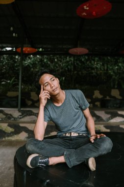 Düşüncelere dalmış Güneydoğu Asyalı bir adam işaret parmağıyla kafasına dokunuyor.