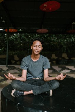 Güneydoğu Asyalı bir adam huzurlu ve düşünceli bir şekilde meditasyon yapıyor..