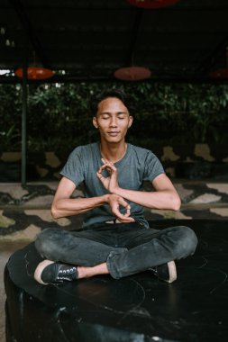 Güneydoğu Asyalı bir adam huzurlu ve düşünceli bir şekilde meditasyon yapıyor..
