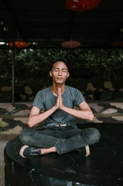 Güneydoğu Asyalı bir adam huzurlu ve düşünceli bir şekilde meditasyon yapıyor..