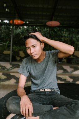 Güneydoğu Asyalı bir adam saçını iki eliyle tutuyor, odaklanmış görünüyor.