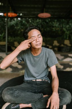 Gözlerini ovuşturan Güneydoğu Asyalı bir adam yorgun ya da uykulu görünüyor.