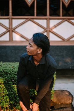 Güneydoğu Asyalı bir adam ayakkabılarını giyerken dikiliyor.