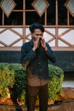 Hapşırığın ortasında, doğal bir ifadeyle yakalanmış Güneydoğu Asyalı bir adam.