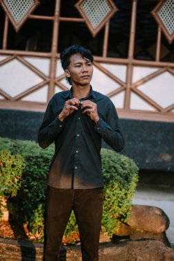 Güneydoğu Asyalı adam gömleğini ilikliyor, odaklanmış ve sakin. Giyinme, hazırlık veya profesyonellik gibi konular için ideal