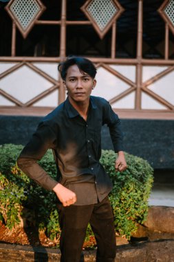 Kolları açık, dövüşmeye hazır Güneydoğu Asyalı bir adam. Yoğun duruş ve kararlı ifade, eylem, nefsi müdafaa veya dövüş sanatları teması için mükemmel.