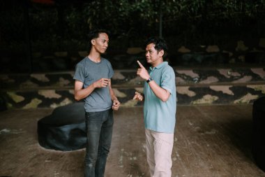 İki Güneydoğu Asyalı adam canlı sohbete daldı, fikirleri ve kahkahaları paylaştılar. Arkadaşlık, iletişim ve sosyal etkileşim temaları için ideal