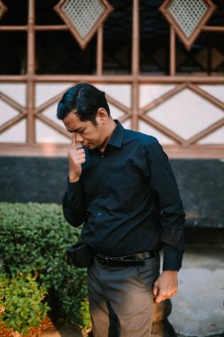 Southeast Asian man holding his forehead, appearing stressed or thoughtful. Perfect for themes of worry, problem-solving, or frustration clipart