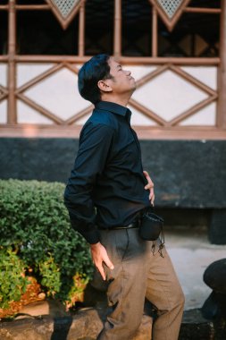 Suratı asık Güneydoğu Asyalı bir adam, sanki acilen tuvalete gitmesi gerekiyormuş gibi karnını tutuyor. Rahatsızlık, aciliyet ya da mizah konuları için ideal