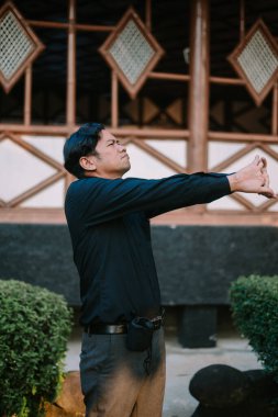 Güneydoğu Asyalı adam belini tutuyor, esniyor ya da rahatlıyor gibi görünüyor. Fiziksel gerginlik, sırt ağrısı veya rahatlama konuları için ideal.