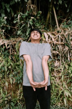 Güneydoğu Asyalı adam rahatlamış görünürken sırtını esnetiyor ve bir anlık rahatlık gösteriyor. Rahatlama, esneme ve refah temaları için idealdir