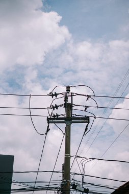 Elektrik direği ve elektrik hatları bulutlu bir gökyüzüne karşı siluetlendi.