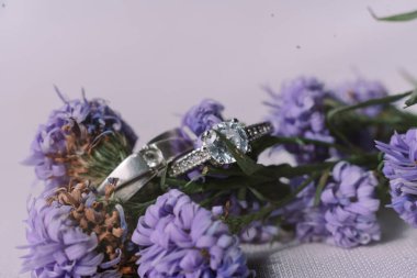 Narin mor çiçeklerin arasına yerleştirilmiş zarif gümüş alyanslar. Aşkın ve bağlılığın sembolü..