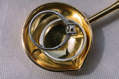 Birbirine dolanmış iki alyans, bir altın ve bir gümüş, altın kaşığa yerleştirilmiş, sonsuz aşkı temsil ediyor..