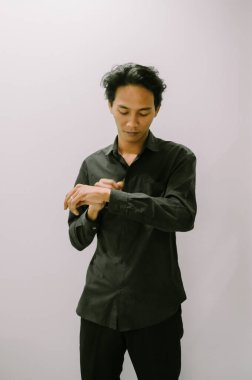 Siyah gömlekli adam kelepçelerini minimalist bir geçmişe göre ayarlıyor.