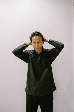 Siyah gömlekli, elleri saçlarının arasında koşan bir adam..