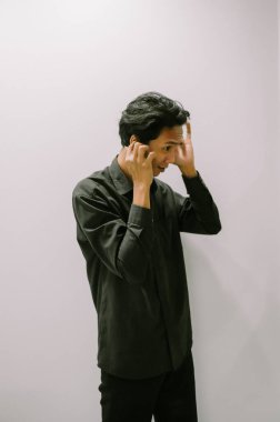 Kulakları elleriyle kapatan adam, siyah gömlek, basit fon..