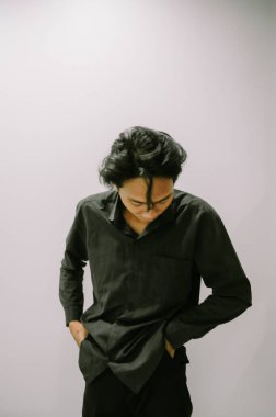 Elleri ceplerinde, siyah gömlekli sıradan bir adam..