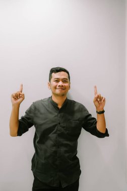 Genç bir adam yukarıya doğru işaret eder, yukarıdaki bir şeye dikkat çeker..