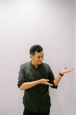 Genç bir adam eliyle bir şey gösterir ya da gösterir..